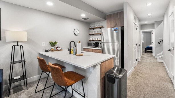 A modern kitchen with a central island, stainless steel appliances, and a clock on the wall.