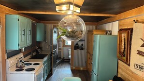 Una cocina compacta con gabinetes verde azulado, una estufa blanca y un refrigerador verde azulado.
