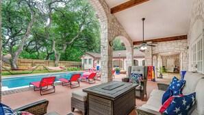 Un patio cubierto con mobiliario exterior, piscina y arquitectura de piedra.