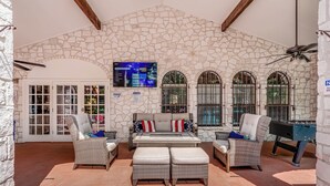 Una habitación con paredes de piedra, un sofá, dos sillones y una mesa de fútbol.