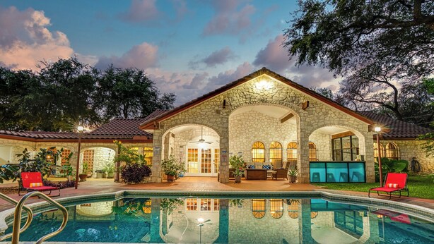 Un edificio de piedra con piscina, mobiliario exterior y un patio.
