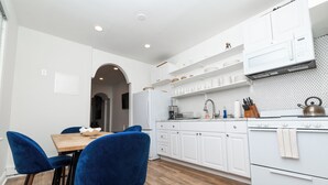 Una cocina moderna con armarios blancos, una mesa de comedor de madera y sillas azules.