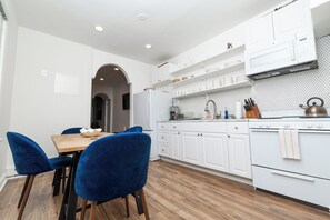 Eine moderne Küche mit weißen Schränken, einem Holztisch und blauen Stühlen.