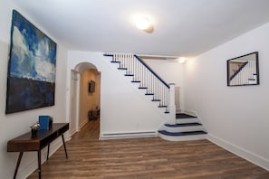 Eine Treppe mit weißen Geländern und blauen Akzenten, ein Holzboden und ein Bild an der Wand.