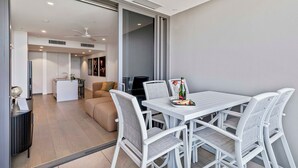 Un comedor moderno con una mesa y sillas blancas, una pequeña isla con un lavaplatos y un sofá al fondo.