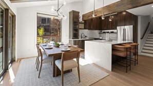 Une cuisine moderne avec des meubles en bois, un îlot en marbre et des luminaires suspendus.