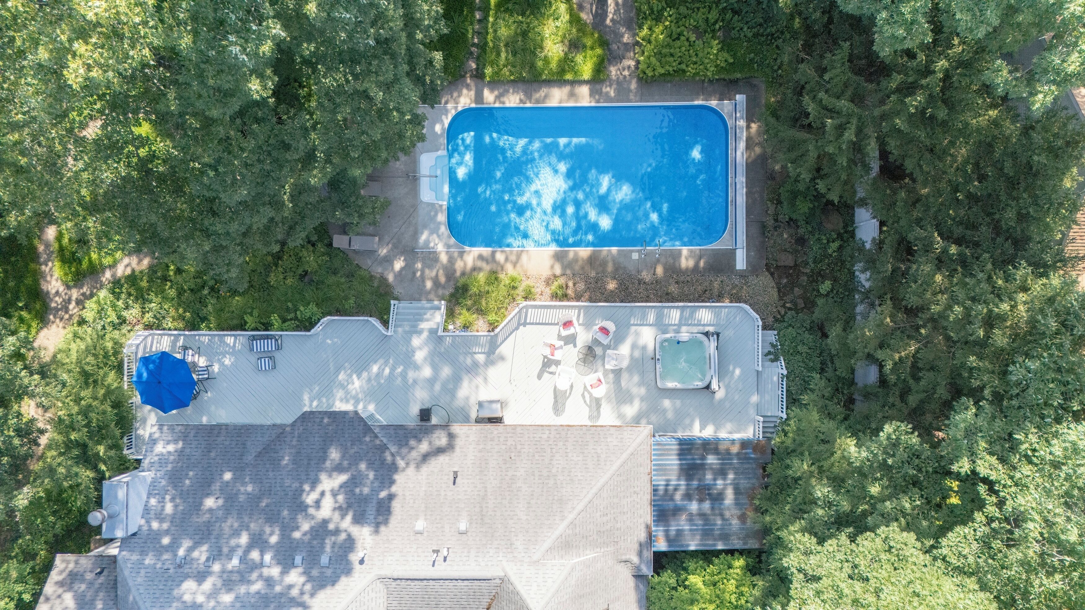 Vista aérea de una casa con piscina, un patio con mobiliario exterior y un jacuzzi.