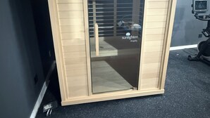 Une pièce dotée d’une armoire aux portes coulissantes en verre, d’un tapis de course et d’une bouche d’aération au plafond.
