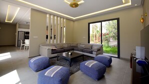 A modern living room with a sectional sofa, a coffee table, and blue poufs.