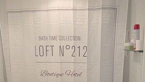 A bathroom with a shower curtain labeled "Bath Time Collection Loft N°212 Boutique Hotel Paris - New York - Roma" and a toilet. - Perfect room for two INDEPENDENT (Albacete)