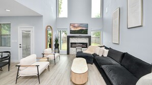 Un salon spacieux avec une cheminée, un grand téléviseur et un coin salon confortable.