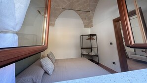A bedroom with a bed, a wardrobe, and a mirror. - Casaggiù traditional house just steps from the towncenter & seaside destinations (San Vito dei Normanni)