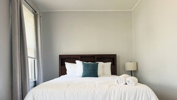 Een hotelkamer met een groot bed, een houten hoofdbord en een nachtkastje met een lamp.