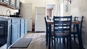 Een compacte keuken met een eethoek, inclusief een koelkast, fornuis en houten stoelen.
