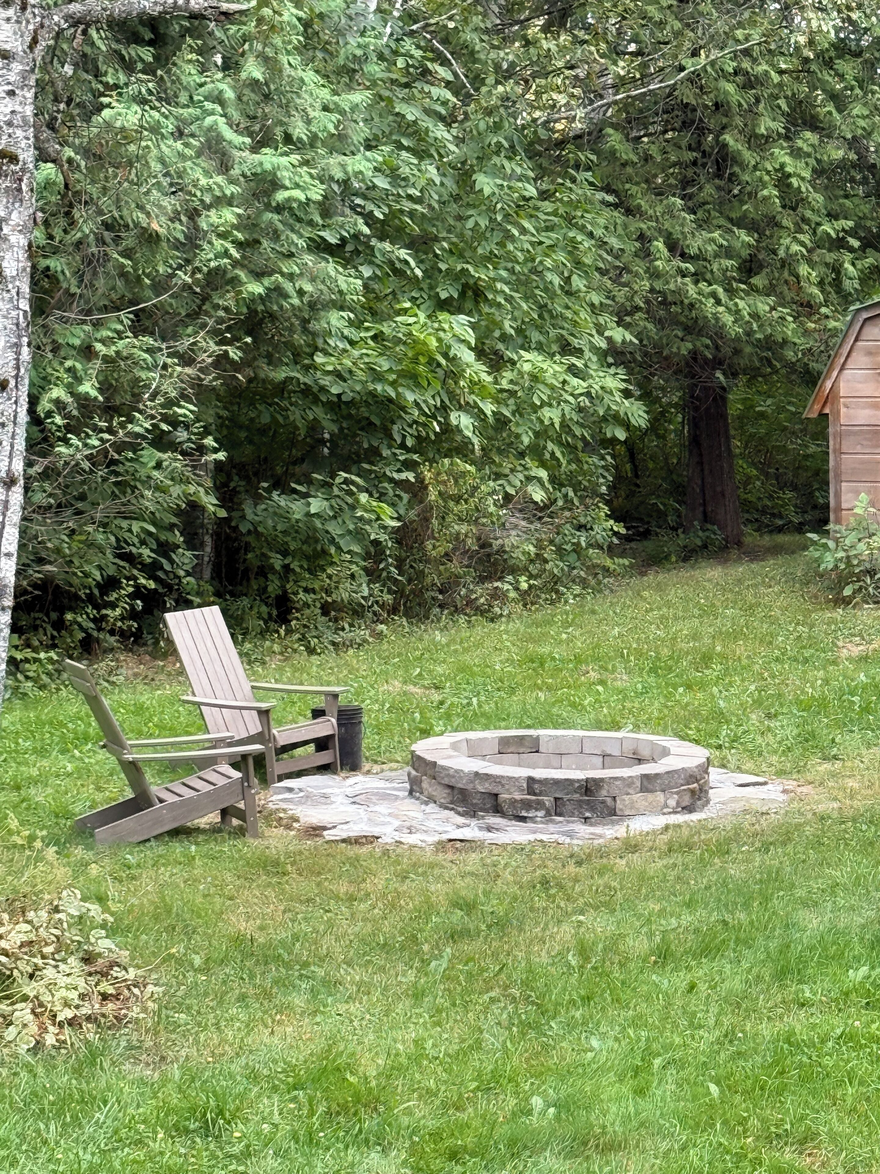 Ein Garten mit einem Holzstuhl, einer Steinkaminkasse und einem Holzschuppen.