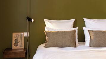 A bed with white bedding and two pillows, a bedside table with a lamp, and a framed picture on the wall.