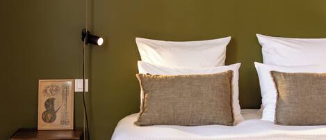 A bed with white bedding and two pillows, a bedside table with a lamp, and a framed picture on the wall.