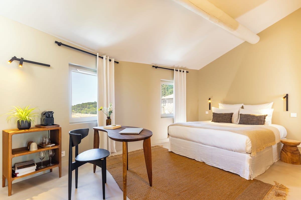 Un dormitorio con cama, escritorio, silla, estantería y ventana.