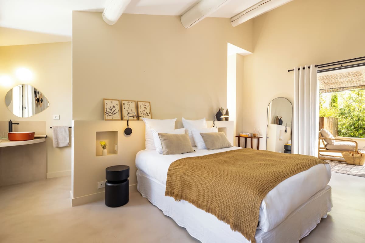 Un dormitorio con una cama grande, mesitas de noche, un espejo y vistas al exterior.