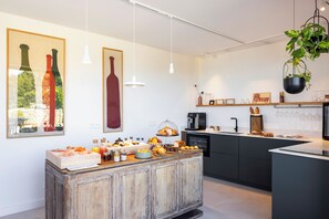 A modern kitchen with a wooden island, pendant lights, and a black countertop. - La Maison des Jardins (Gigondas)