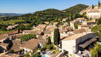 A residential area with traditional architecture, a swimming pool, and a view of the surrounding hills.