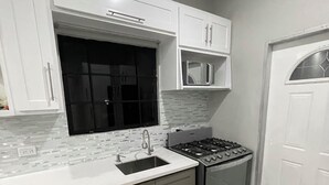 A kitchen with white cabinets, a black window, a microwave, and a stove. - Fantastic modern apartment in Chaguanas (Chaguanas)