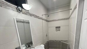 A modern bathroom with a large mirror, a white sink, and a shower area. - Fantastic modern apartment in Chaguanas (Chaguanas)