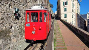 A red tram with the number 2 on a narrow street flanked by stone walls and buildings. - Genova Principe Suite (Genoa)
