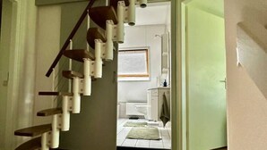 A staircase with wooden steps and white railings leading to a bathroom with a toilet and sink. - Detached country house in Drenthe with large garden, terrace & beautiful views (Schoonloo)