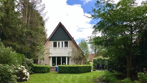A house with a triangular roof, a front porch, and a well-maintained lawn. - Detached country house in Drenthe with large garden, terrace & beautiful views (Schoonloo)
