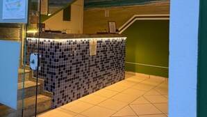 A reception area with a tiled wall, a counter, and a staircase leading to an upper level.