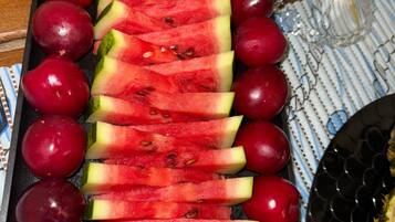 Uma bandeja com melancia fatiada e uvas vermelhas sobre uma toalha estampada.