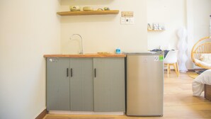 A compact kitchen with a built-in refrigerator, a sink, and a wooden shelf above. - Romantic Studio with Sunlight in the City Center (Hồ Chí Minh)