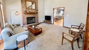 A living room with a fireplace, a sofa, a coffee table, and a TV. - 4 Bedroom Family Friendly Home in Great Madison Location (Madison)