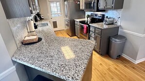 A modern kitchen with granite countertops, stainless steel appliances, and a central island with seating. - 4 Bedroom Family Friendly Home in Great Madison Location (Madison)