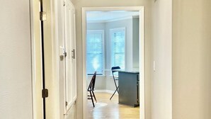 A hallway with wooden flooring and white walls, leading to a room with a desk and chair. - 4 Bedroom Family Friendly Home in Great Madison Location (Madison)
