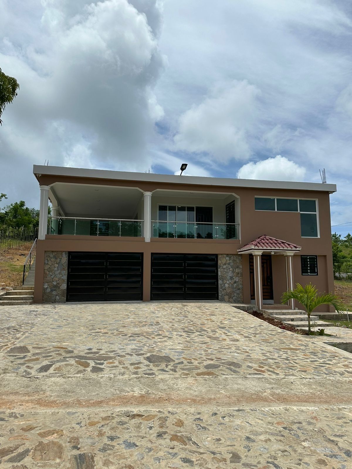 A two-story house with a garage, a covered porch, and a stone-paved driveway.