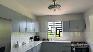 Una cocina moderna con gabinetes grises, encimera de mármol, horno empotrado y ventana con vistas al verdor.