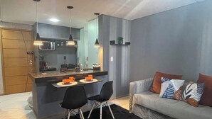 Een moderne keuken met een eethoek, een bank met decoratieve kussens en een zwart vloerkleed.