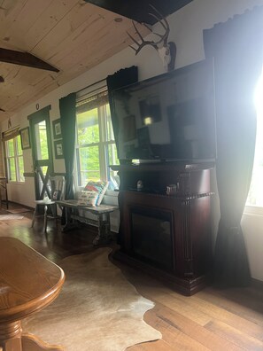 A living room with a fireplace, a television, and a dining area.