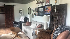 A living room with a sofa, a brown leather chair, a wooden coffee table, a ceiling fan, and a fireplace. - Fisherman’s paradise waterfront. Boat ramp on property sleeps 6.      2-2.  (Many)