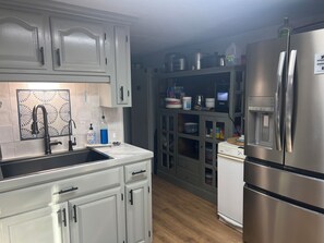 A modern kitchen with white cabinetry, a stainless steel refrigerator, and a built-in oven.