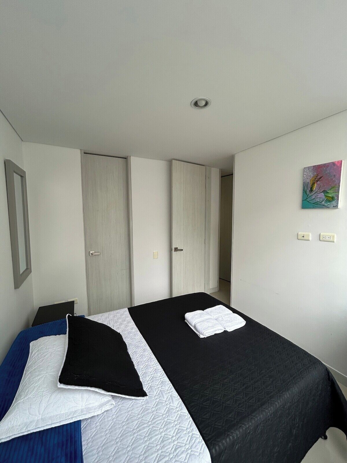A bedroom with a bed, a wardrobe, and a painting on the wall.
