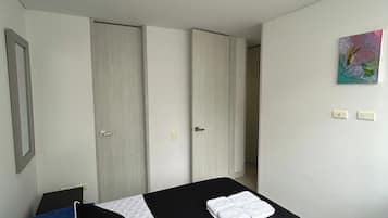 A bedroom with a bed, a wardrobe, and a painting on the wall.