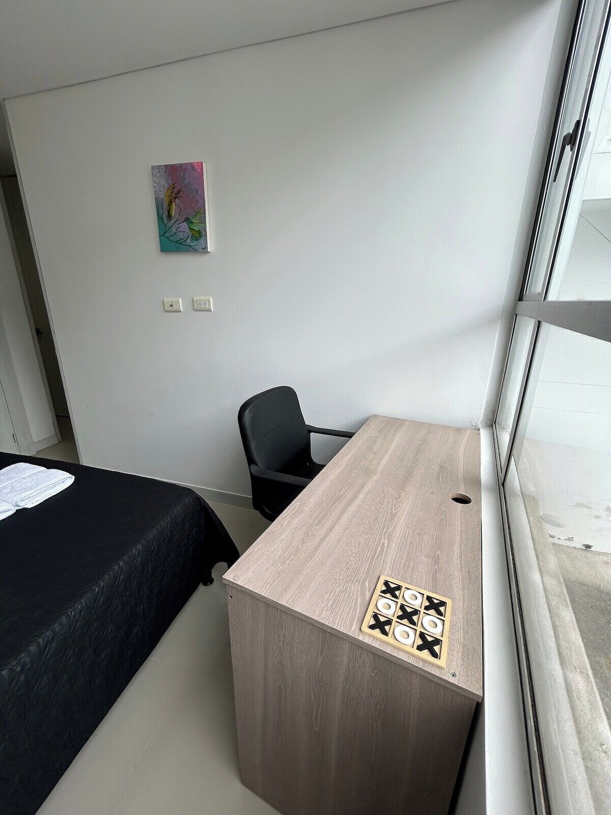 Hotellihuone, jossa on sänky, työpöytä, tuoli ja ikkuna.