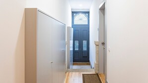 A narrow hallway with a wooden floor, a blue door with decorative glass panels, and a small rug at the entrance. - Modern Retro Downtown by LovelyStay (Porto)