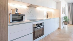 A modern kitchen with white cabinets, a built-in microwave, a sink, and a stove.