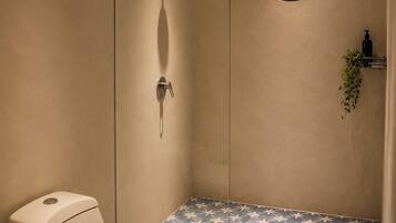 Une salle de bain avec des toilettes, une douche dotée d’une porte en verre et un miroir rond.