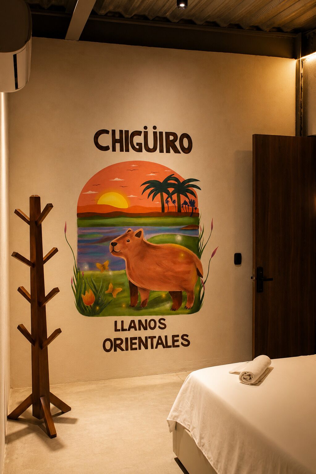 A wall with a mural of a sunset, palm trees, and a hippopotamus, labeled 'CHIGURO' and 'LLANOS ORIENTALES'.