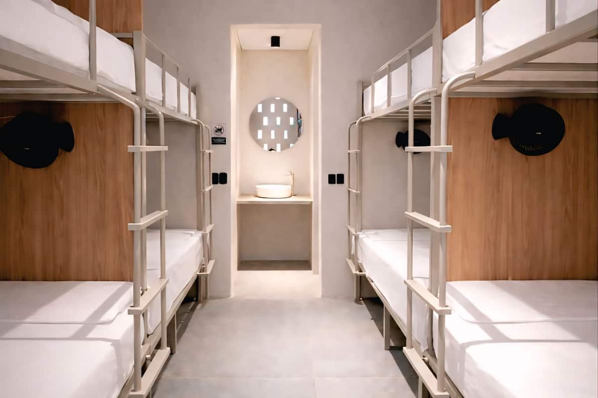 A bunk room with a central sink and a circular mirror on the wall.